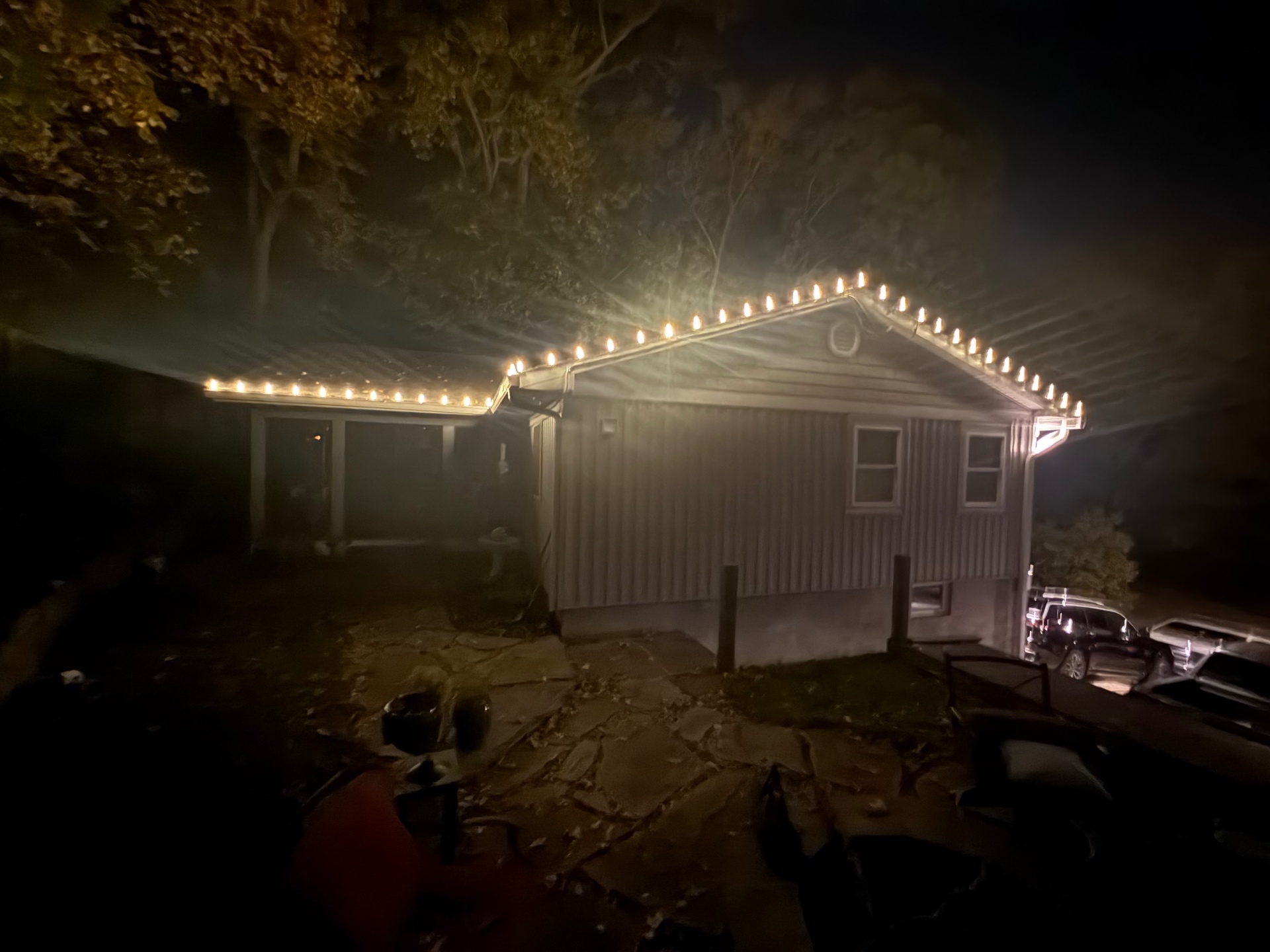 Warm white roofline lights on a small single-story home