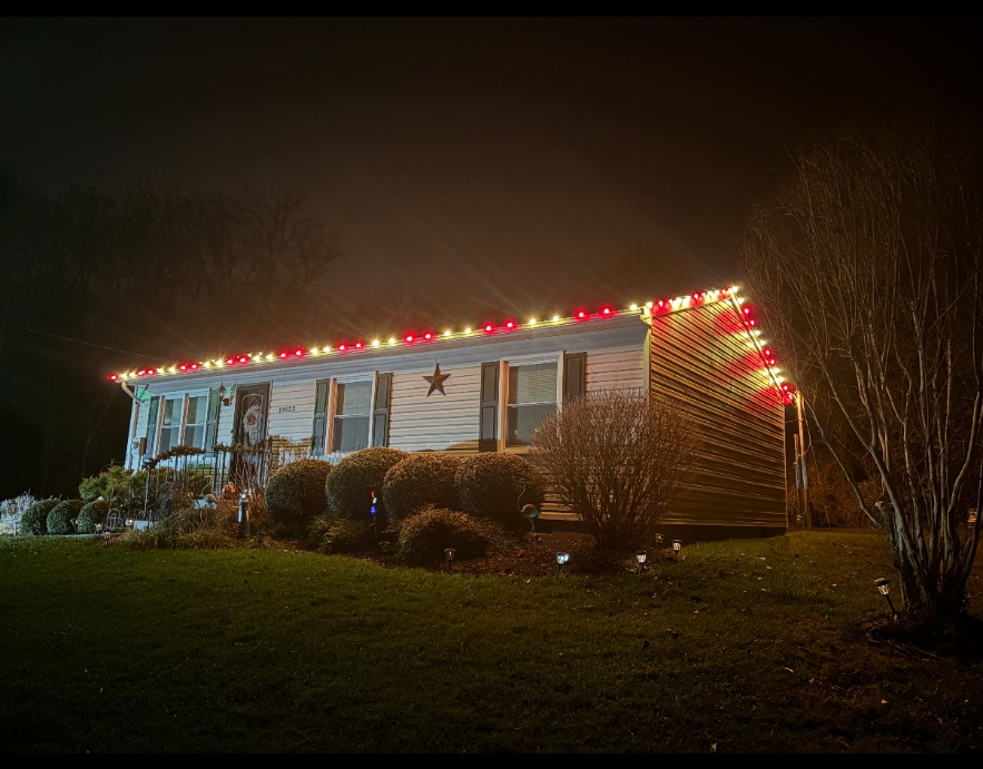 Red and white holiday lights installed along the roof of a single-story home