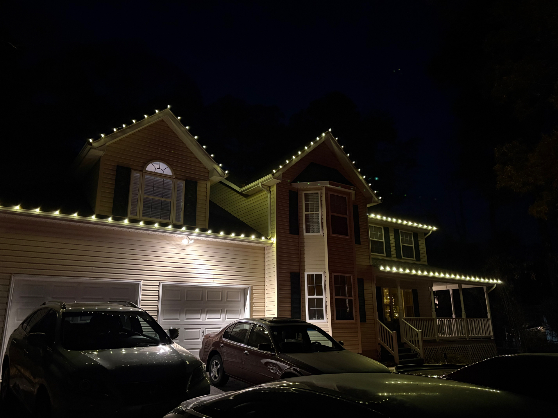 Warm white roofline lights on a two-story home at night