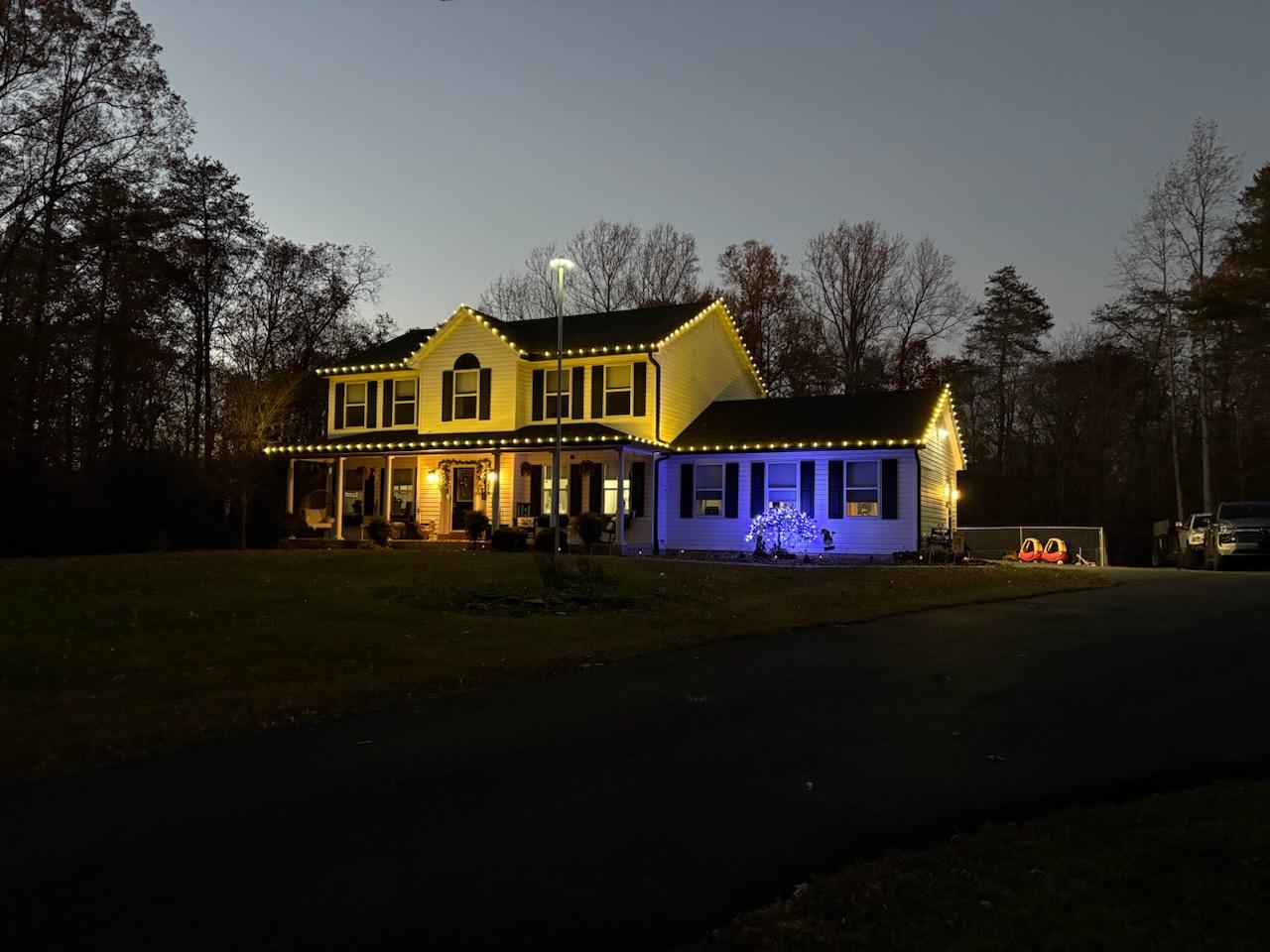 Warm white roofline lights with blue accent lighting on a two-story home at dusk