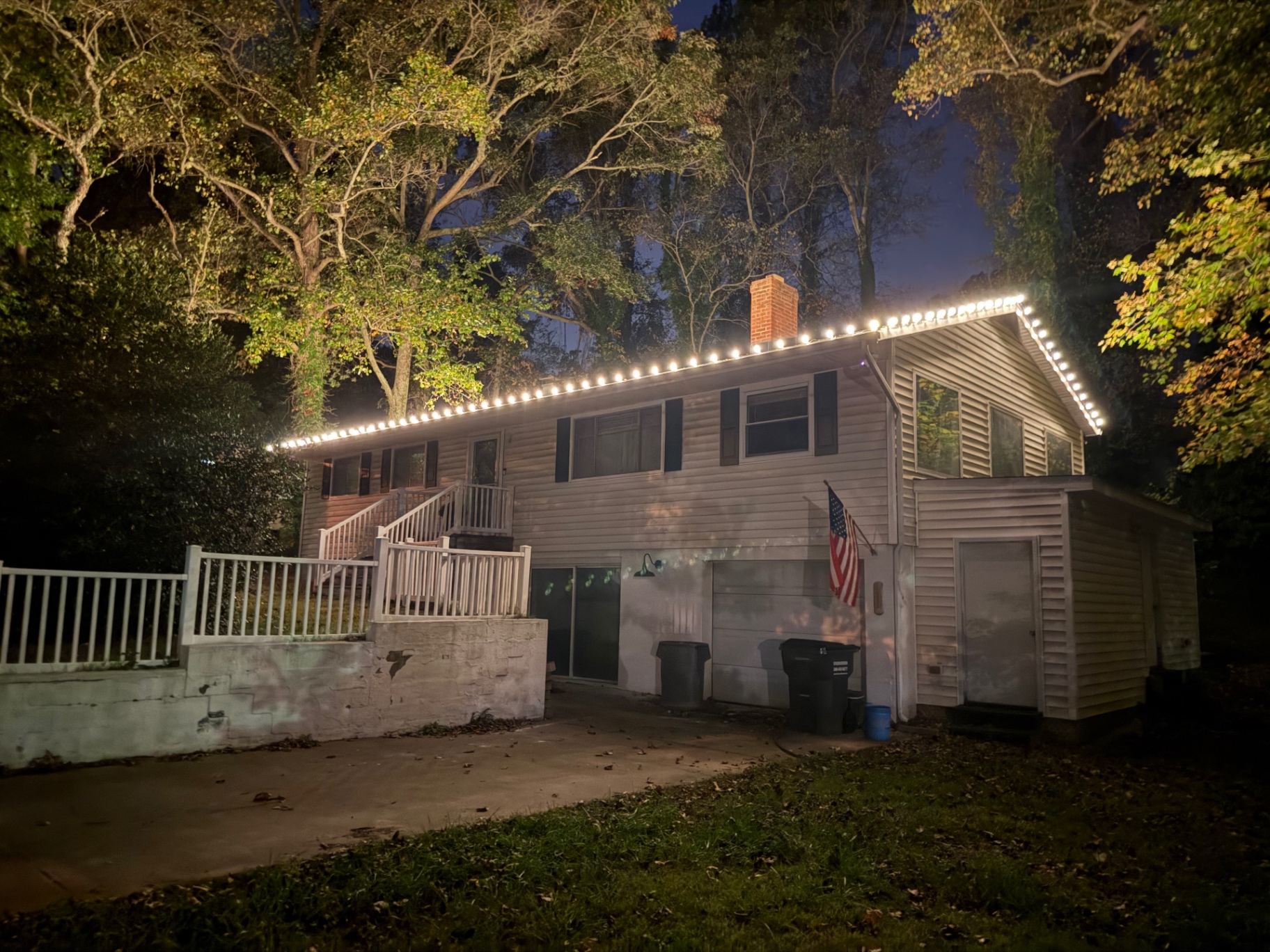 Warm white lights along the roofline of a two-story home with a garage